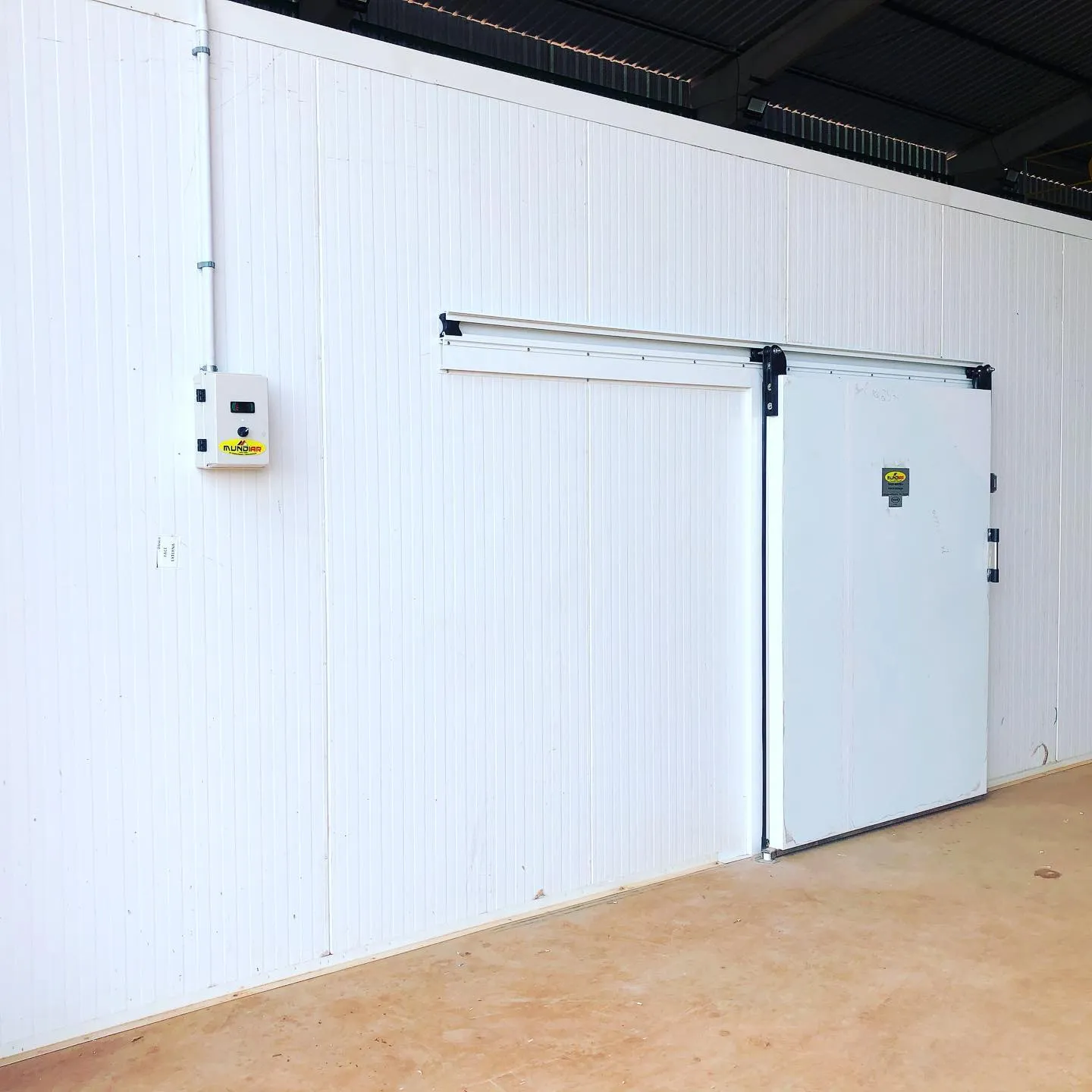 Fachada de câmara fria com porta de correr e painel de controle Mundiar