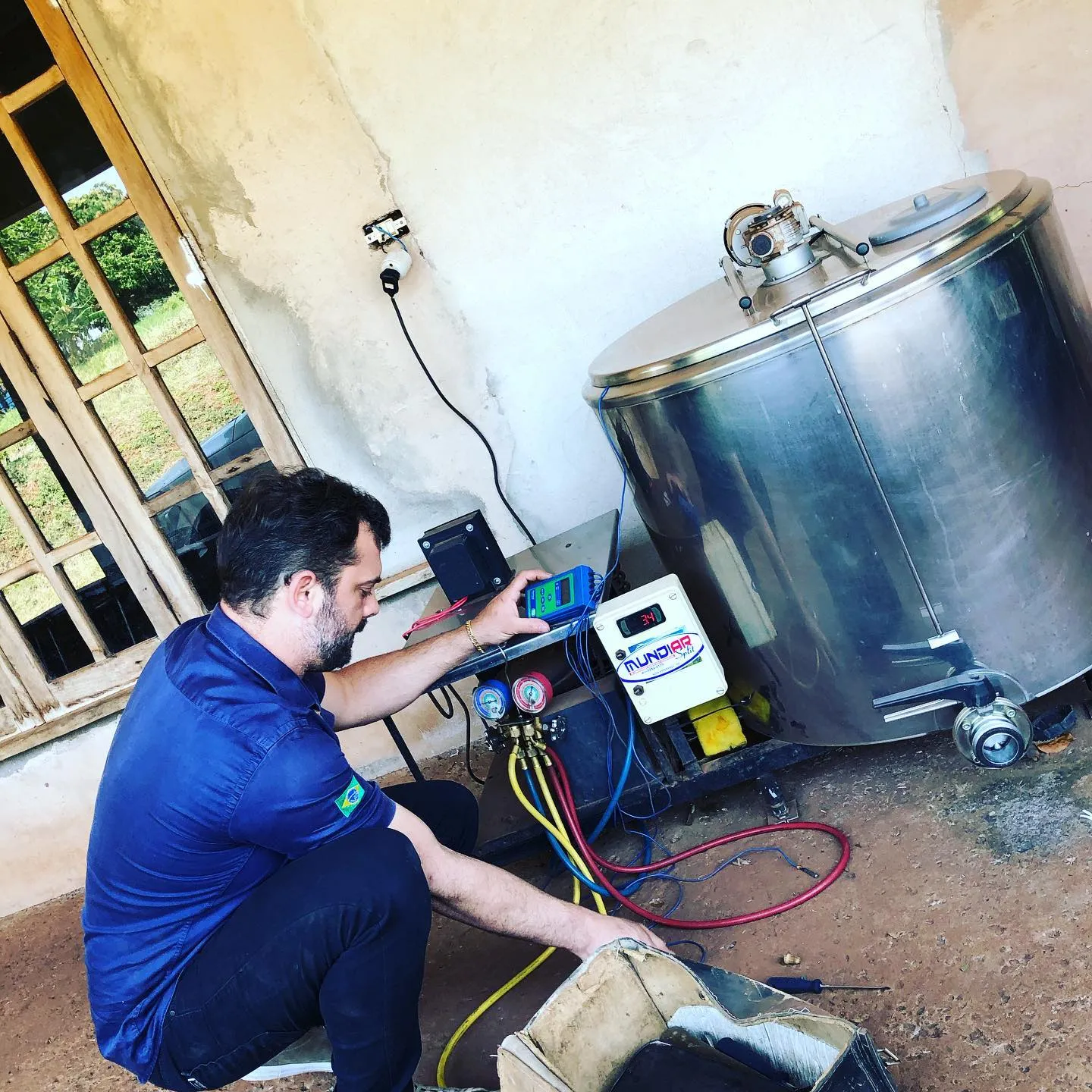 Técnico medindo pressões em tanque resfriador de leite de aço inox