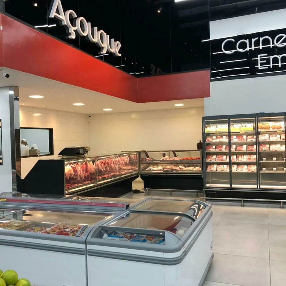 Açougue de supermercado com balcões refrigerados, expositor de carnes e ilhas de congelados
